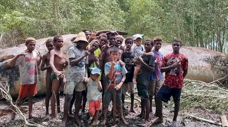 Masyarakat di Muara Fayid Kabupaten asmat saat berpose didepan bangkai Ikan Raksasa/ Ist