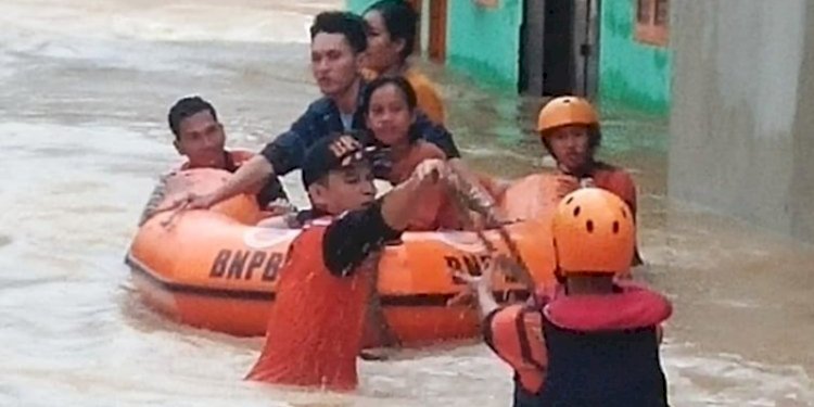 Petugas dari BPBD mengevakuasi warga Muara Enim yang rumahnya terendam banjir, Senin (27/12)/Ist