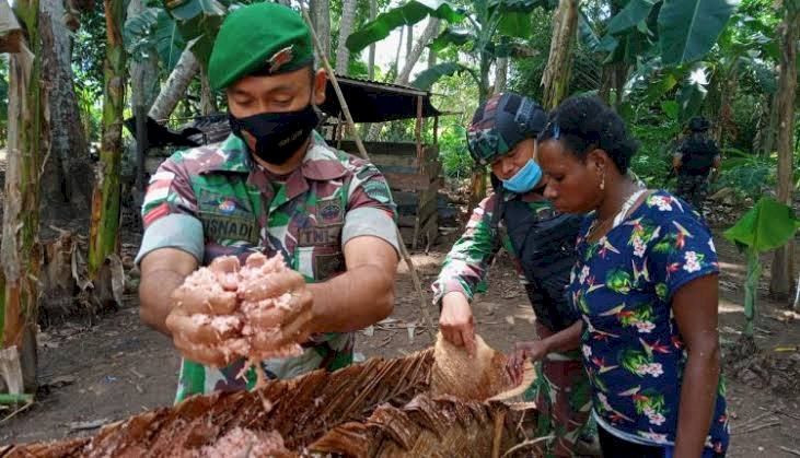 Anggota TNI saat membantu mama Papua mengelola makanan tradisional